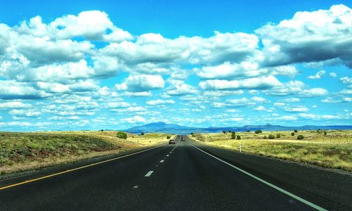 Country road against cloudy sky