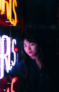 Young woman standing by illuminated text