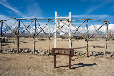 Information sign on fence by land against sky