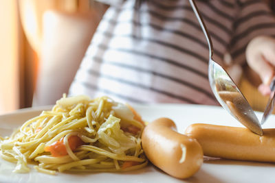 Midsection of woman having sausage at home