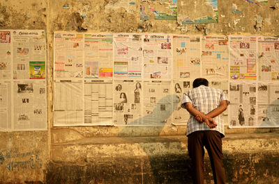 Rear view of man standing against graffiti wall