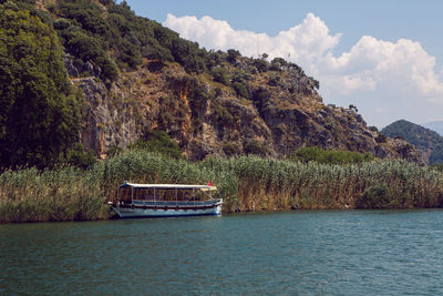 Rowing boat with tourists floating on the river near the lycian tombs in the summer