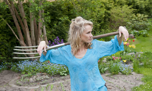 Woman with gardening fork standing in garden