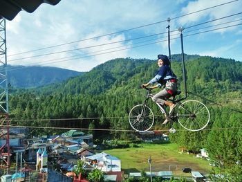 Man riding bicycle on mountain against sky