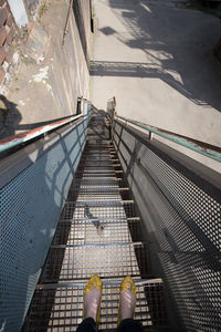 Low section of woman standing on metallic staircase at industrial building