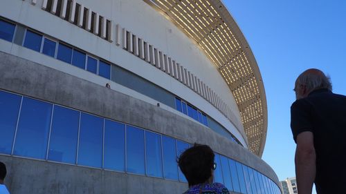 Low angle view of people against clear blue sky