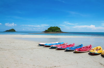 Kayaks at beach against blue sky