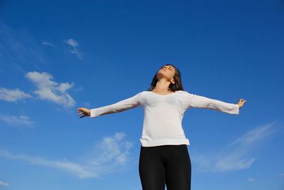 Low angle view of woman standing against blue sky