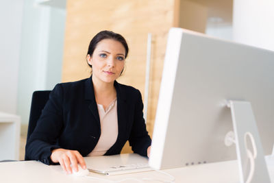 Young woman using mobile phone while sitting in office