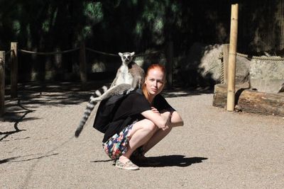 Full length portrait of woman sitting with a lemur in a backpacker