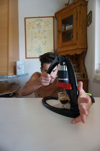 Portrait of man drinking coffee cup on table at home