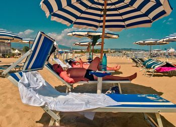 Chairs and tables on beach against sky