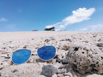 Close-up of sunglasses on beach against blue sky