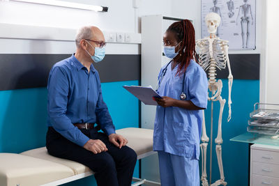 Nurse wearing mask examining patient in clinic