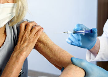 Cropped hand of doctor vaccinating woman at hospital