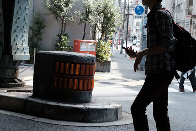 Rear view of woman standing on sidewalk in city