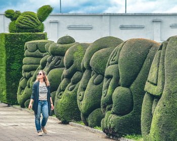 Full length of woman wearing sunglasses walking on footpath