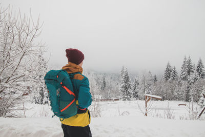 Rear view of man standing on snow covered landscape