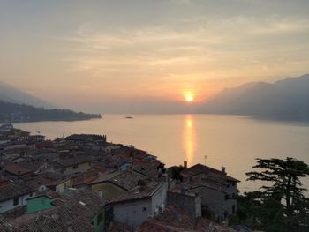 Scenic view of sea by buildings against sky during sunset