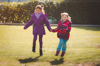 Full length of happy girls running on field