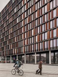 People riding bicycle on street against buildings in city