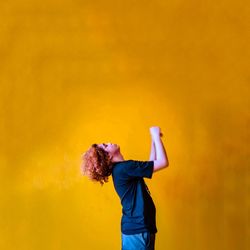 Full length of man standing against yellow wall