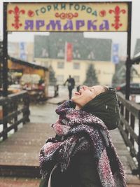 Side view of woman with eyes closed sticking out tongue during snowfall