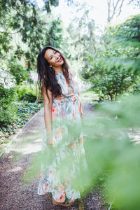 Happy mixed-race japanese woman in romantic floral maxi dress in summer park