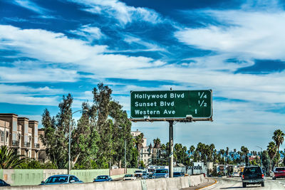 Information sign by road against sky