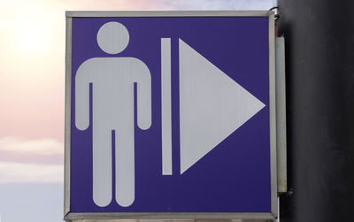 Close-up of arrow sign against blue sky