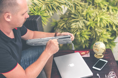 Midsection of man using mobile phone while sitting on table