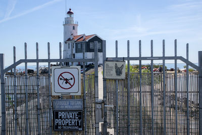 Information sign on fence against sky