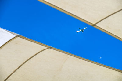 Low angle view of airplane flying against clear blue sky