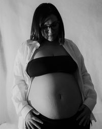 Portrait of pregnant woman standing against wall