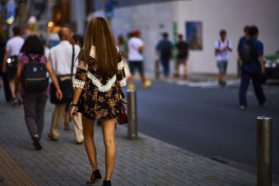 People walking on sidewalk by road in city