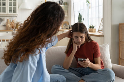 Side view of woman using mobile phone while sitting at home