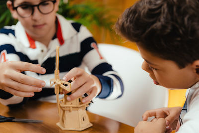 Close-up of male friends making toy windmill on table at home
