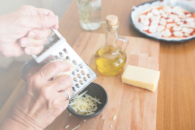 Close-up of woman grating cheese on table