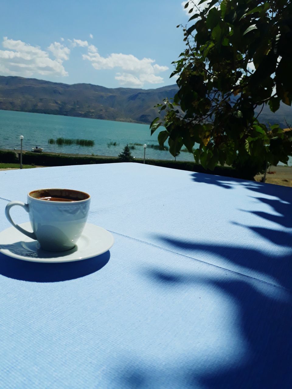COFFEE CUP ON TABLE AGAINST MOUNTAIN