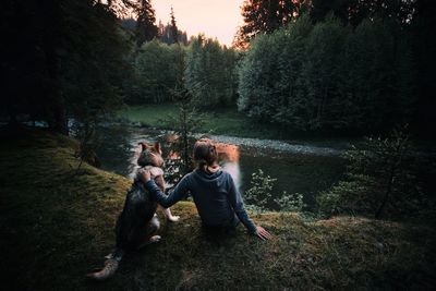 People sitting on dog by lake in forest