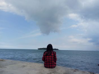 Rear view of woman on beach against sky