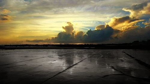 Scenic view of wet shore against sky during sunset