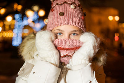 Close-up portrait young girl in knitted hat holds her hands in mittens near