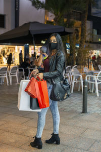 Woman with long black hair, wearing a mask for protection against covid-19 shopping 