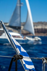 Greek flag fluttering in the wind on a sailing yacht sailing on the blue sea against the blue  sky