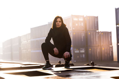 Young female runner takes a break on a freight train in the commercial port in the morning