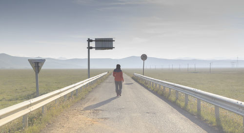 Rear view of man standing on road against sky