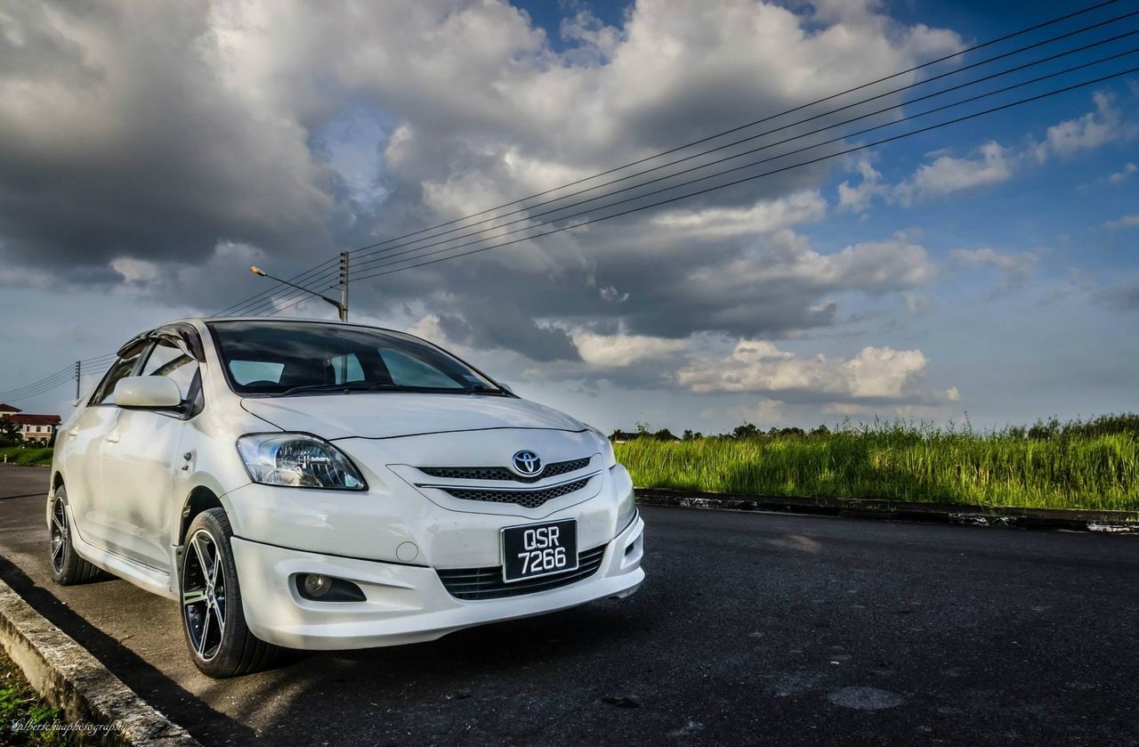 transportation, sky, cloud - sky, mode of transport, land vehicle, road, car, cloudy, cloud, power line, electricity pylon, travel, street, day, landscape, field, outdoors, on the move, tree, journey