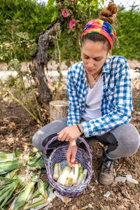 High angle view of woman putting vegetables in basket outdoors