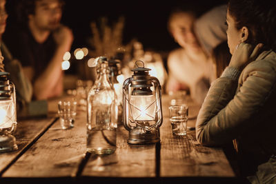 People sitting around illuminated table in restaurant at night